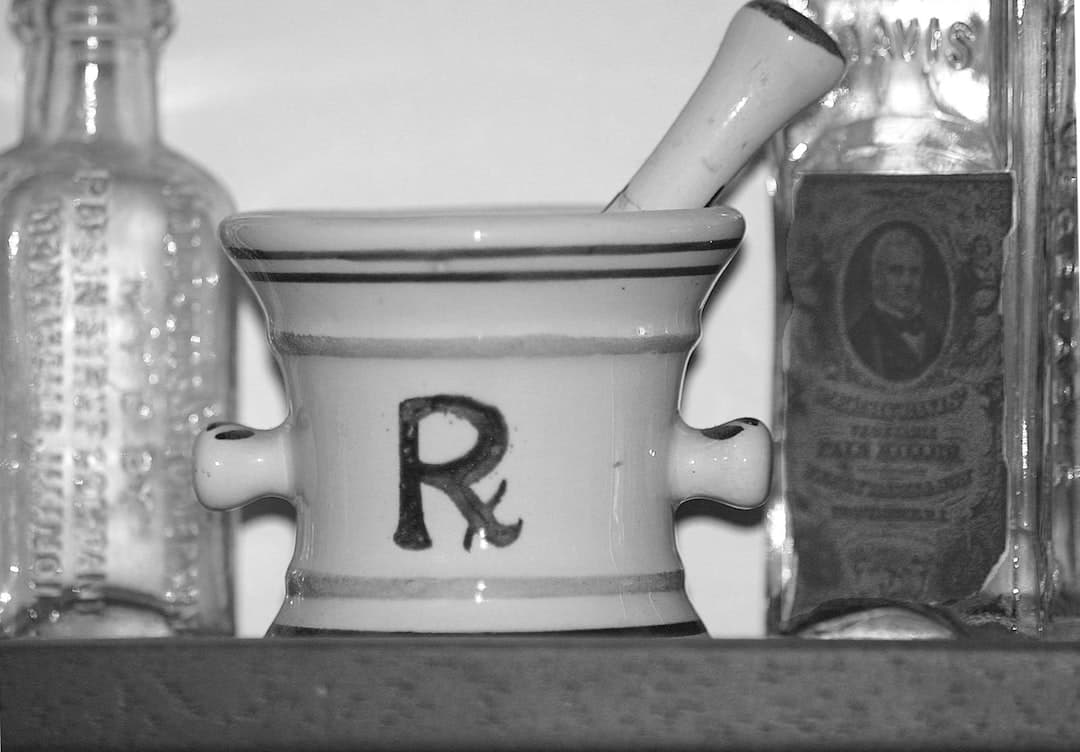 A black and white photo of bottles and a mortar